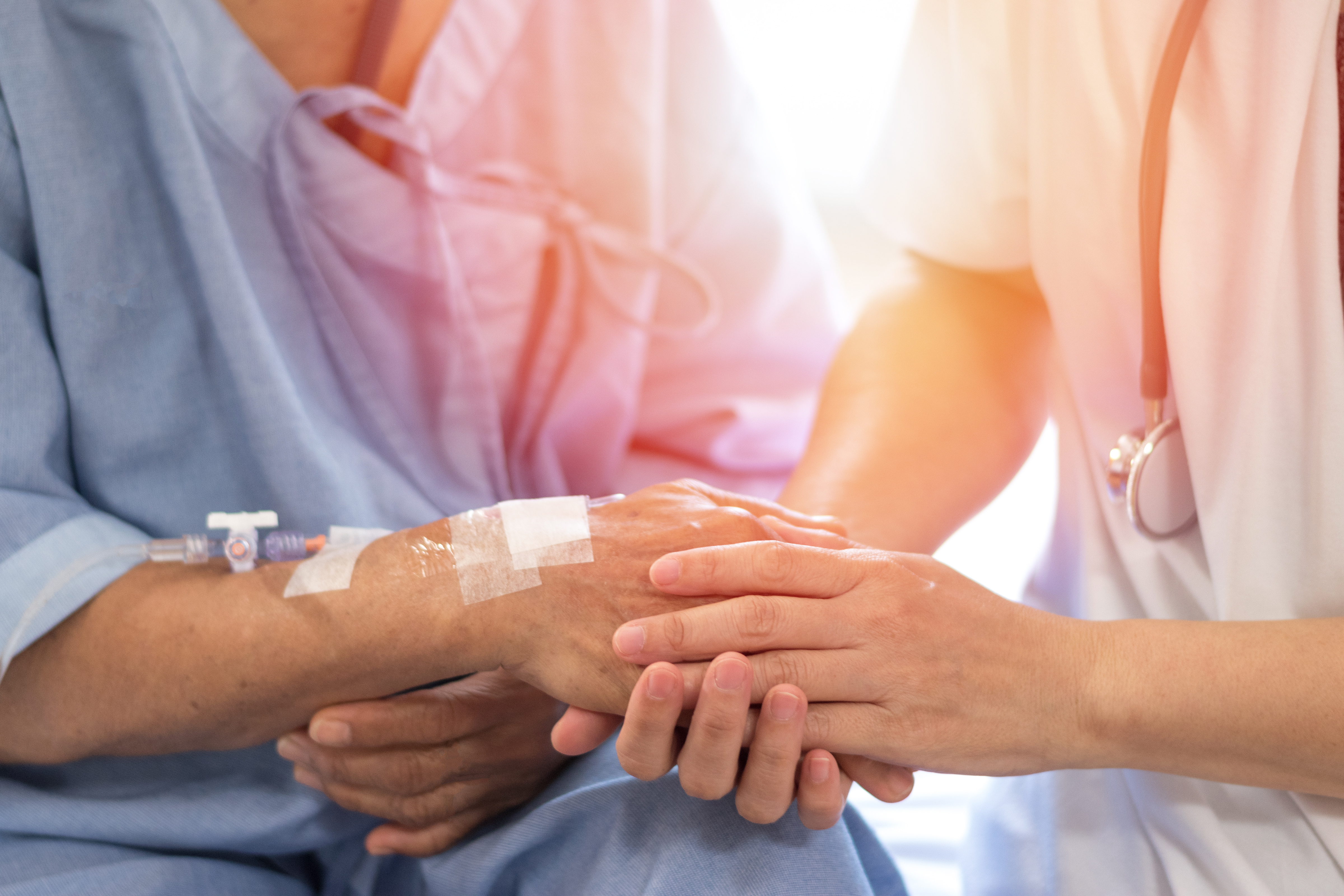 Closeup image of a doctor's hand holding patient's hand in comforting way