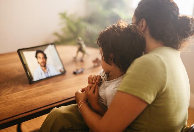 A mother and child use a tablet to e-visit the doctor