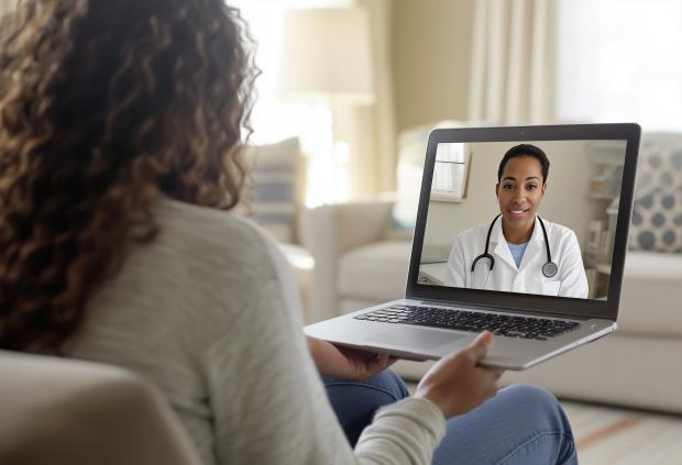 Adult female patient talks to her physician on a video call on her laptop