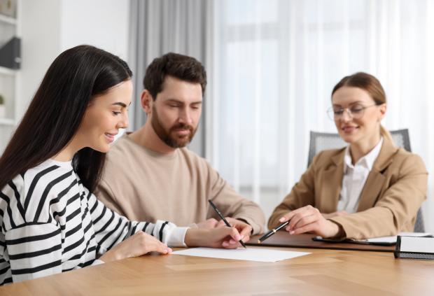 Smiling couple completes paperwork with attorney