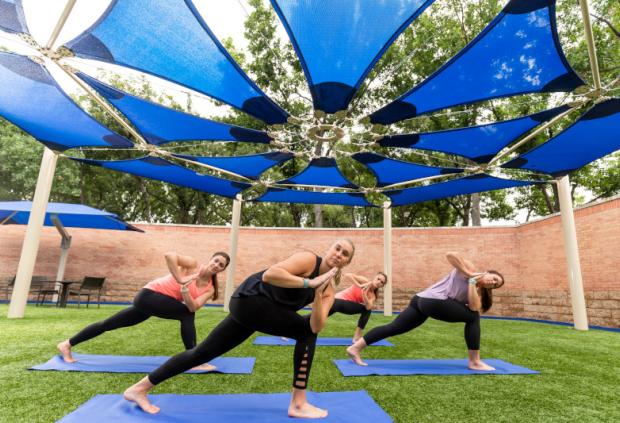 A group of women take an outdoor yoga class at HealthZone Saint Francis Tulsa