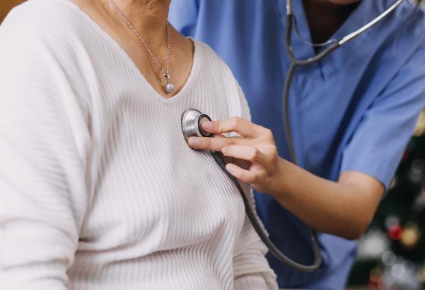 Closeup of doctor listening to adult female patient's heartbeat with a stethoscope