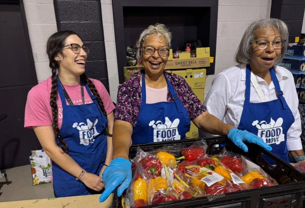 Three Saint Francis Day volunteers smile while working at a food bank