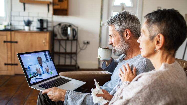 A couple has a virtual appointment with their doctor using their laptop. 