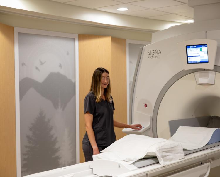 Female technician standing next to MRI machine at Saint Francis