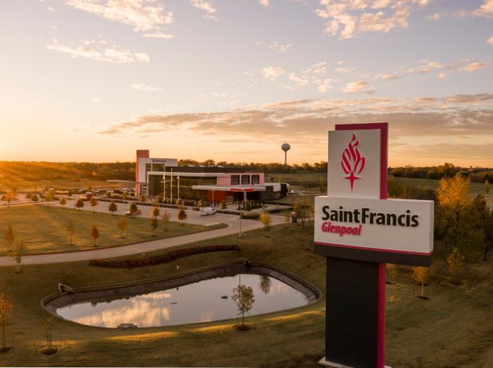 Exterior, aerial view of Saint Francis Glenpool building, sign and pond in warm sunset
