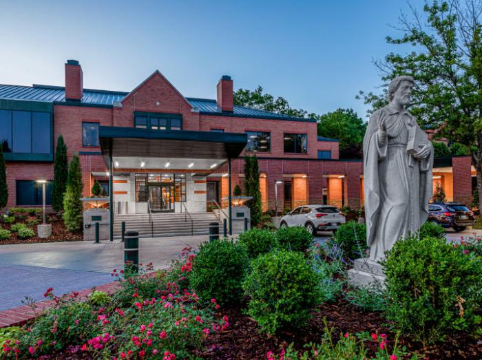Exterior view of Laureate main entrance with Saint Francis Xavier Statue at dusk