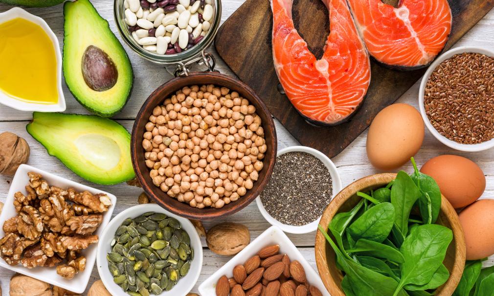 A table full of healthy foods like salmon, spinach and avocado