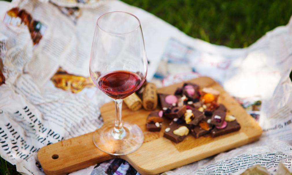 A tasting board with a glass of red wine and pieces of chocolate