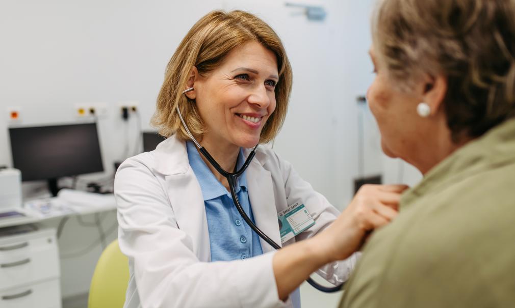 Smiling doctor listens to patient's heartbeat with stethoscope