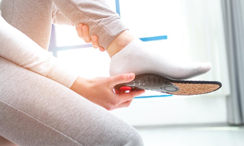 A person measures an arch support insert against their foot