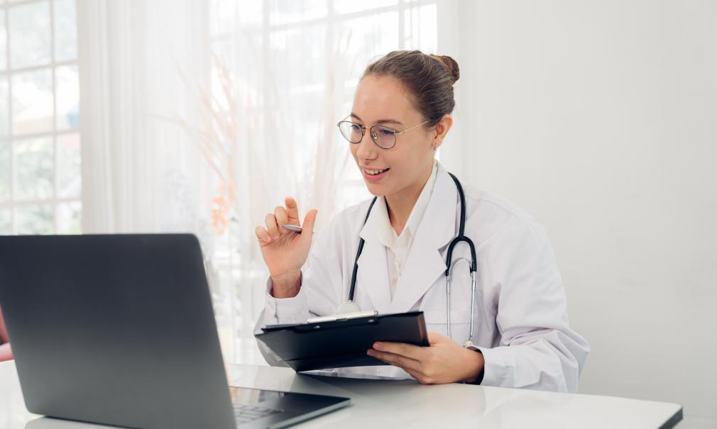 Smiling doctor greets patient on a virtual visit with her laptop
