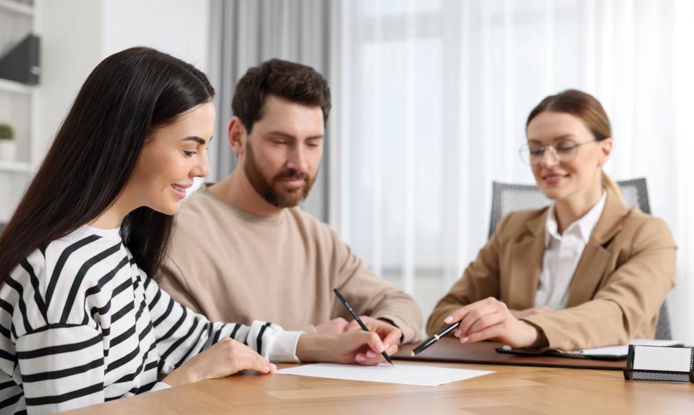 Smiling couple completes paperwork with attorney