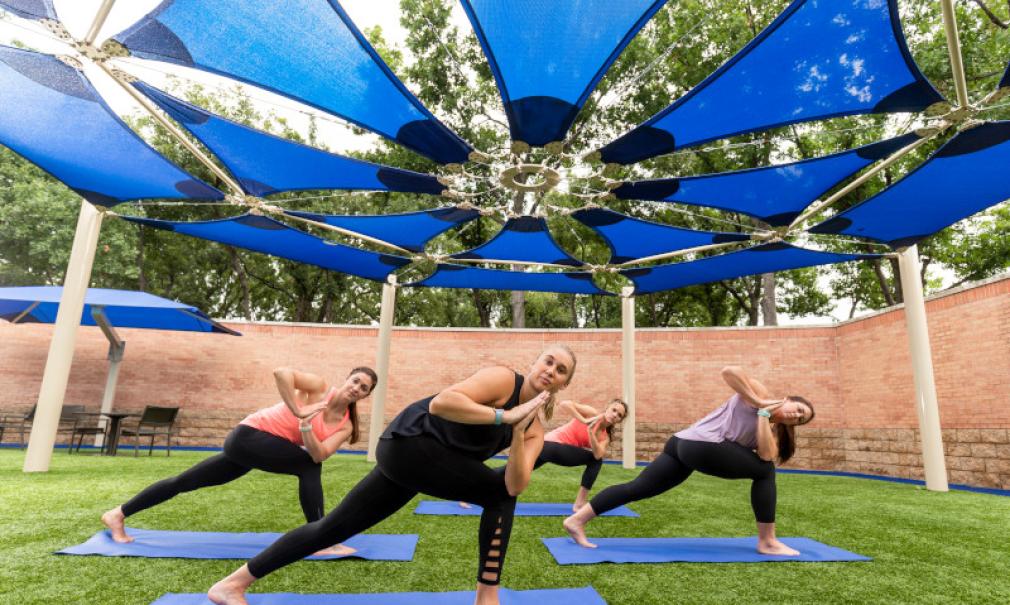 A group of women take an outdoor yoga class at HealthZone Saint Francis Tulsa