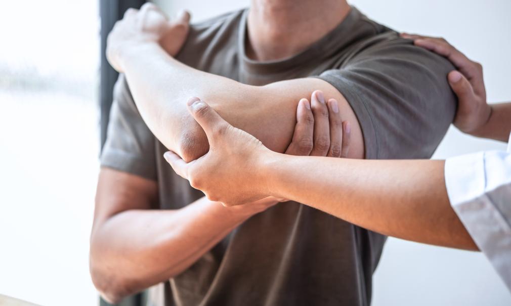 Closeup of therapist assisting patient with shoulder stretch