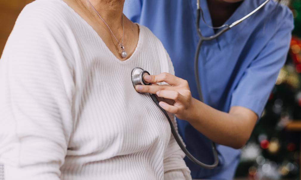 Closeup of doctor listening to adult female patient's heartbeat with a stethoscope