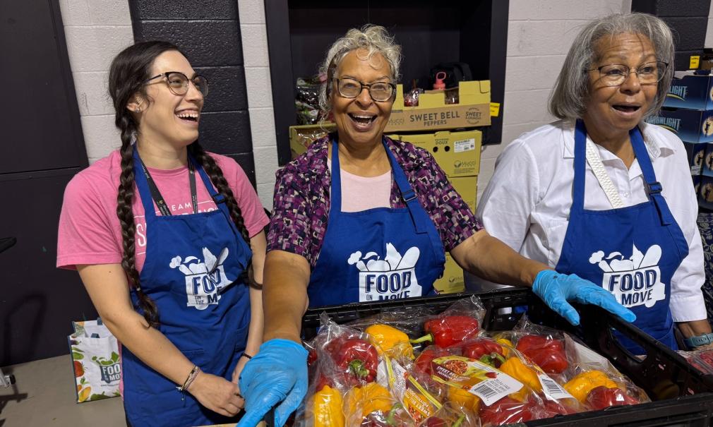 Three Saint Francis Day volunteers smile while working at a food bank