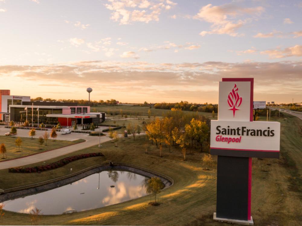 Exterior view of Saint Francis Glenpool with pond, sign and sunset