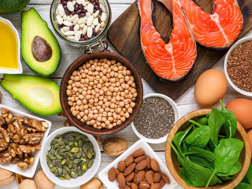 A table full of healthy foods like salmon, spinach and avocado