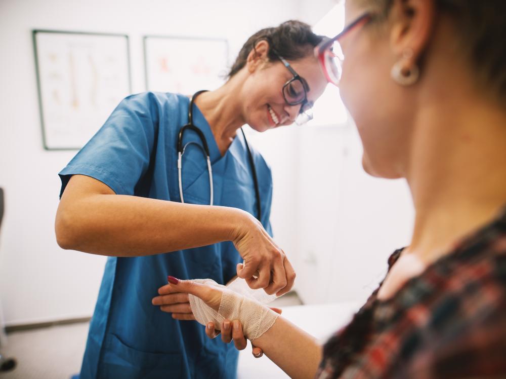 Smiling nurse applies bandage to patient's hand