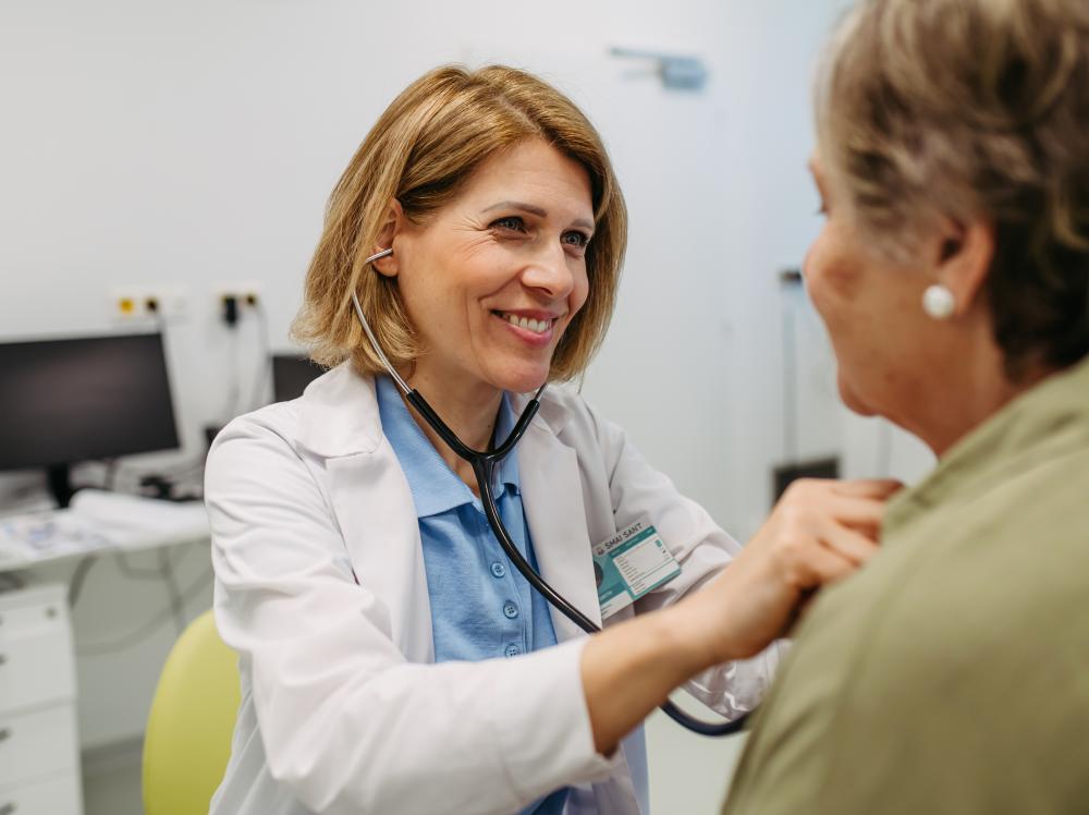 Smiling doctor listens to patient's heartbeat with stethoscope