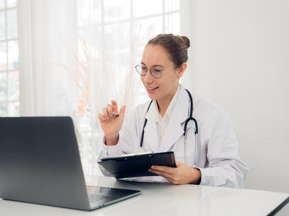 Smiling doctor greets patient on a virtual visit with her laptop