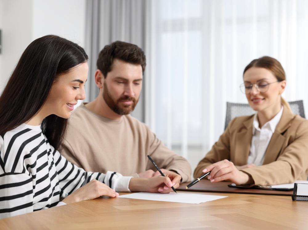 Smiling couple completes paperwork with attorney