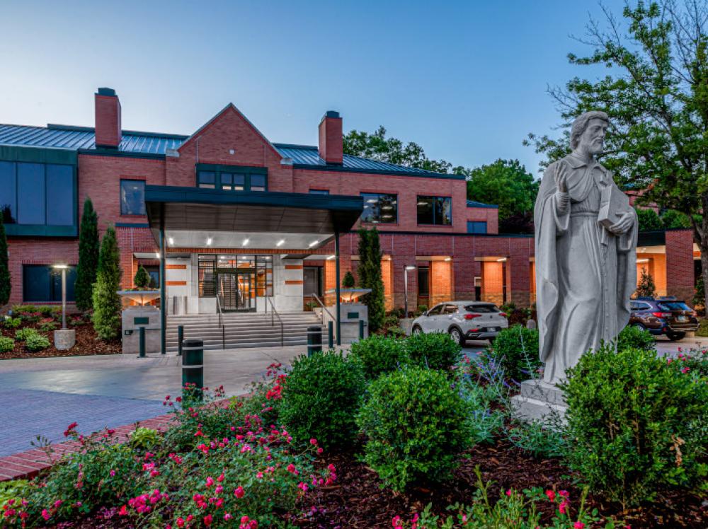 Exterior view of Laureate main entrance with Saint Francis Xavier Statue at dusk