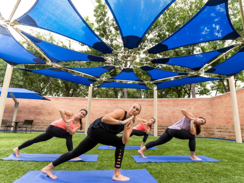 A group of women take an outdoor yoga class at HealthZone Saint Francis Tulsa