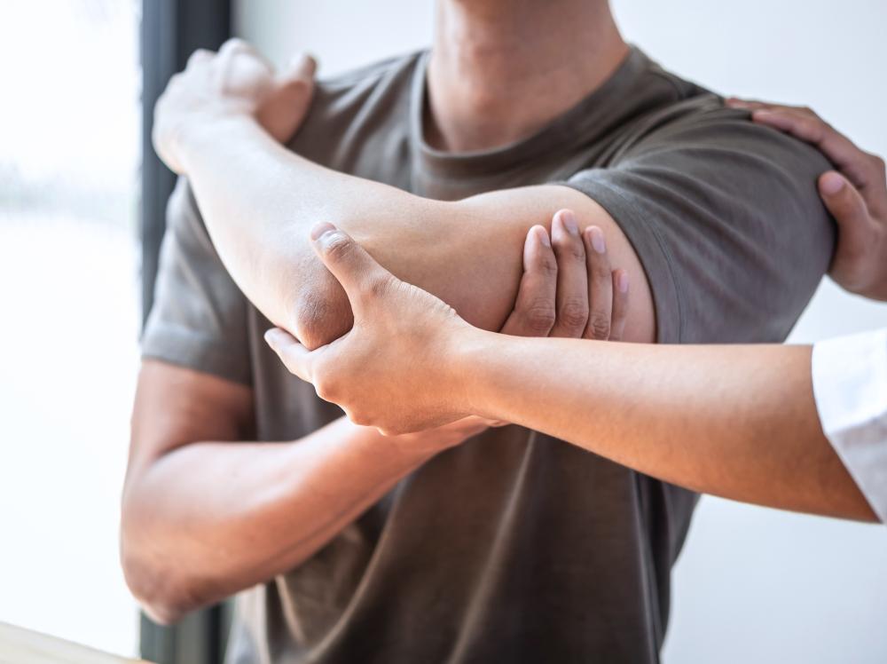 Closeup of therapist assisting patient with shoulder stretch
