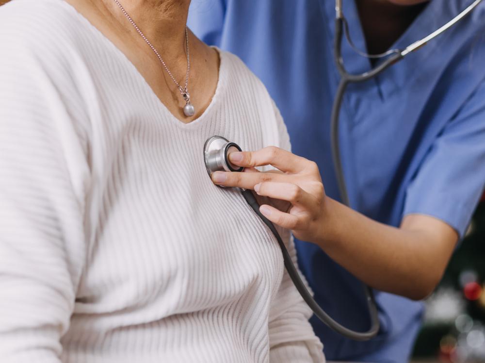 Closeup of doctor listening to adult female patient's heartbeat with a stethoscope