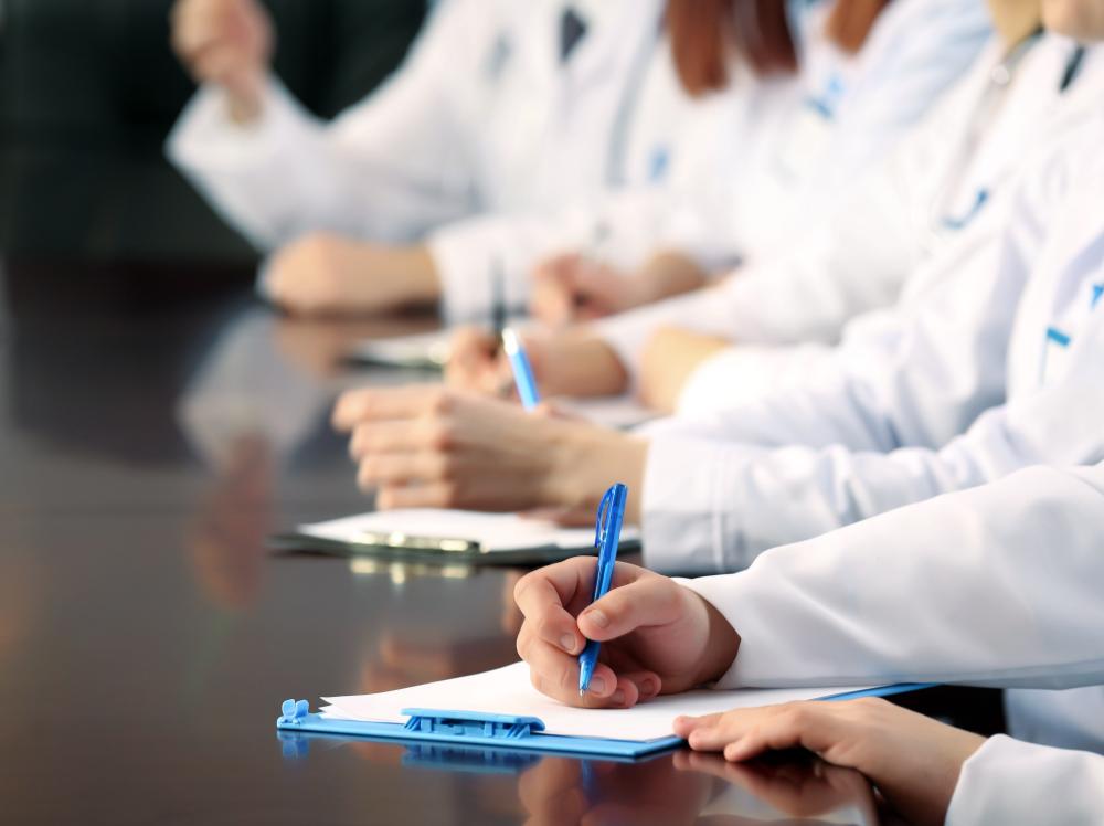 Stock image of white-coated doctors taking notes on clipboards at a table