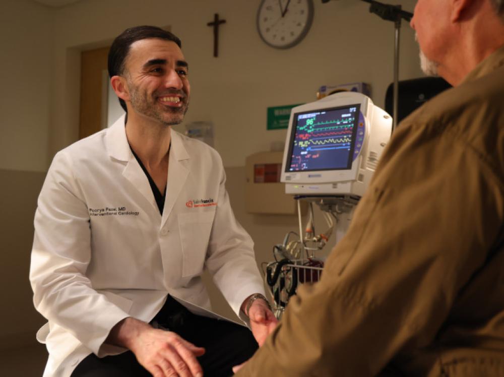 Doctor Fazel smiles while talking to an adult patient in clinic