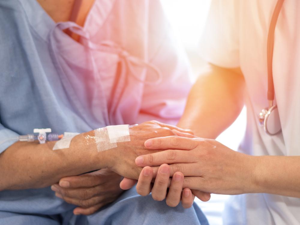 Closeup image of a doctor's hand holding patient's hand in comforting way