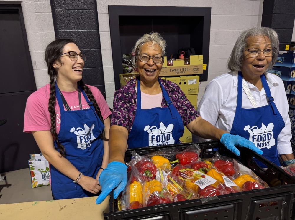 Three Saint Francis Day volunteers smile while working at a food bank