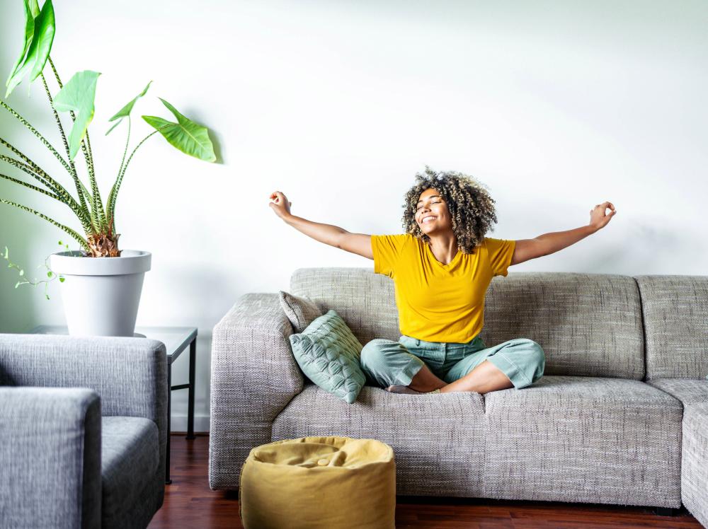 Woman smiles and stretches her arms in a cozy sunlit living room